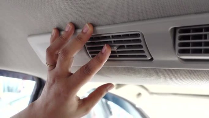 女人把手放在汽车空调格栅窗格上，