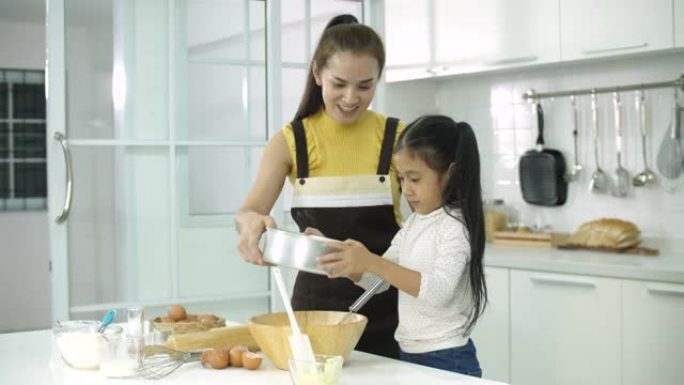 年轻的母亲与女儿在厨房里度过时光，为饼干做面团