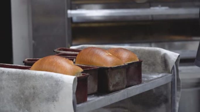 面包师从仍然很热的模具中取出新鲜制作的面包