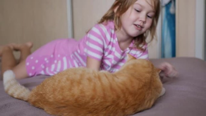 可爱的小女孩躺在床上的姜猫上