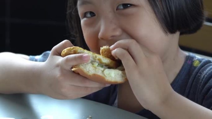 微笑的中国孩子吃美味的汉堡