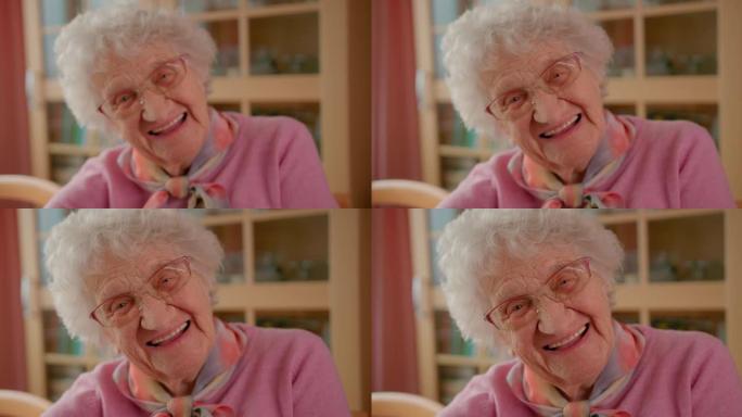 一位快乐的老年妇女的肖像，满头白发看着相机，洁白的牙齿微笑。