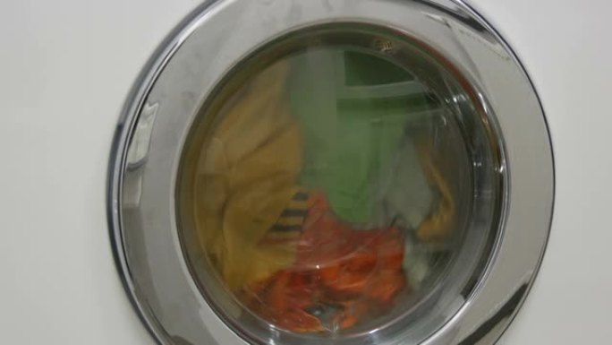 多色衣物洗衣房在白色洗衣机中洗涤。