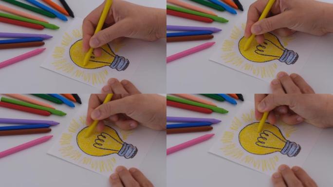女人用黄色蜡笔给灯泡画上色。