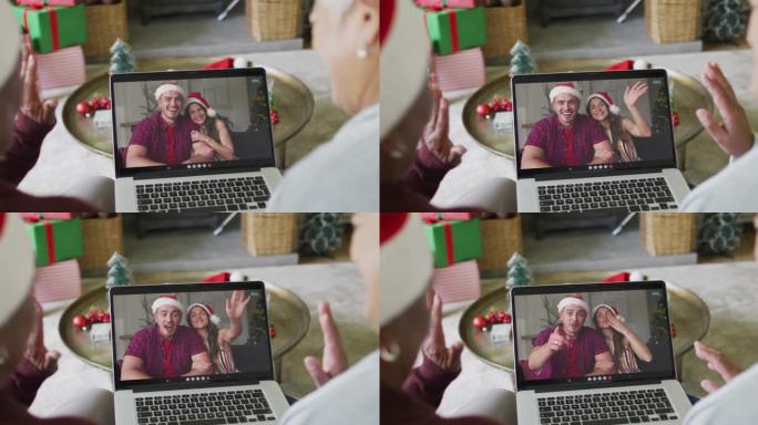 多元化的资深女性朋友挥舞着并使用笔记本电脑与屏幕上的情侣进行圣诞节视频通话