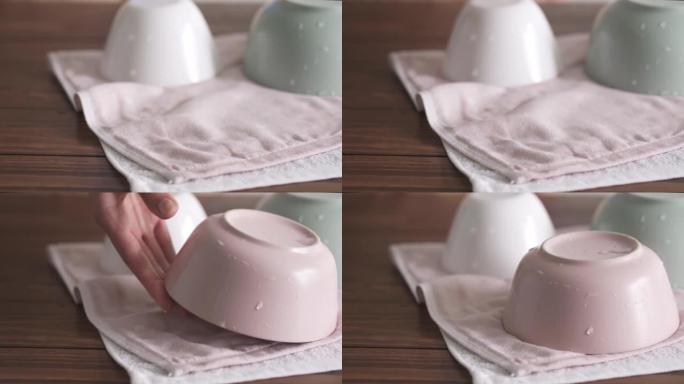 用茶巾清洁潮湿的盘子。粉红色和绿色的陶器。柔和颜色的陶瓷餐具。三个不同的空冰沙碗