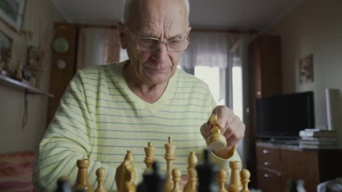 戴眼镜的白发老人在棋盘上移动主教棋子