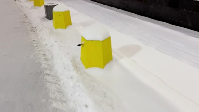 停车场的混凝土围栏在傍晚的雪下呈黄色圆柱体的形式