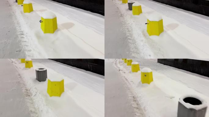 停车场的混凝土围栏在傍晚的雪下呈黄色圆柱体的形式