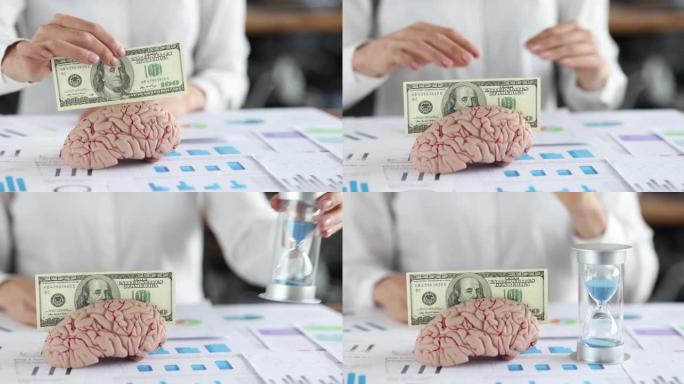女人的手将百美元的钞票放入人脑模型中