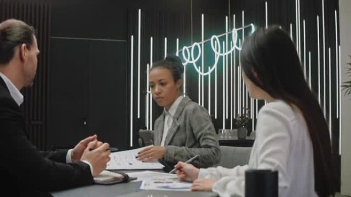 女人参加会议并与灰色办公室的同事分享信息