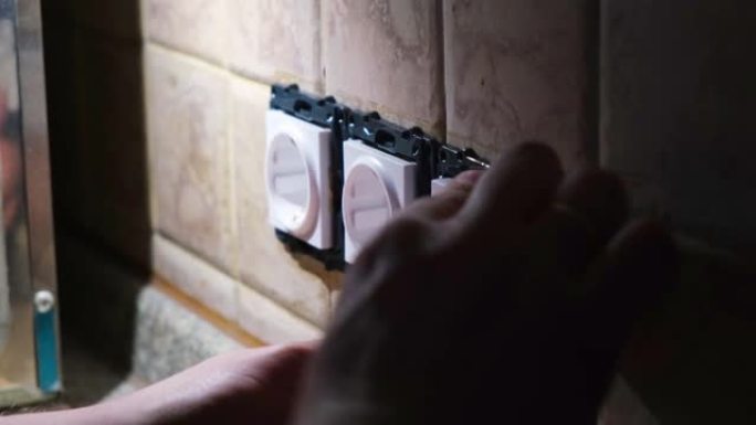 电工在黑暗中修理公寓的电源插座。静态镜头。家居装修概念