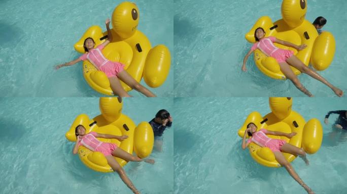 快乐的亚洲女孩在游泳池里的黄鸭橡皮筏上放松，与家人一起度假，生活方式理念。