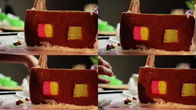 孩子的手工制作姜饼屋与姐姐在晚上在家，圣诞节庆祝生活方式的概念。