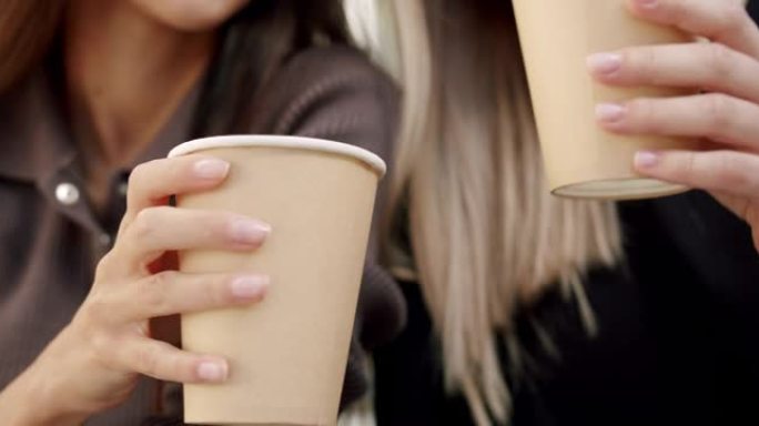 特写，两个漂亮的女孩在夏日用纸杯喝彩咖啡饮料