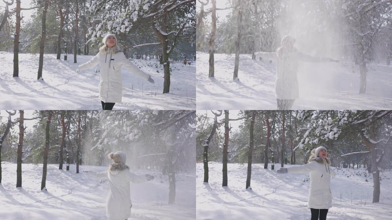 快乐的微笑女孩在飘落的雪中欢欣鼓舞。白色的雪花在太阳的光芒中闪闪发光。从白雪覆盖的树上落下的雪。美丽