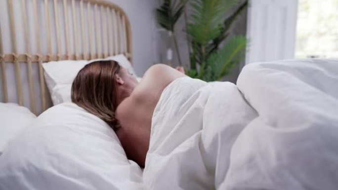年轻漂亮的女人独自睡在舒适的床上。裸女在明亮舒适的卧室。早晨健康休息，无衣入梦
