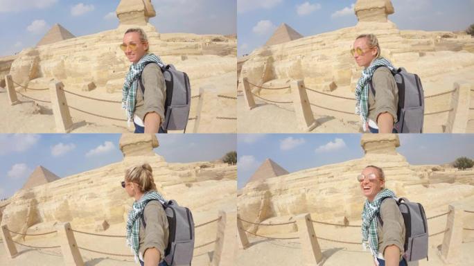 年轻女子在埃及开罗与狮身人面像在大金字塔合影。在埃及拍照的女人会观光