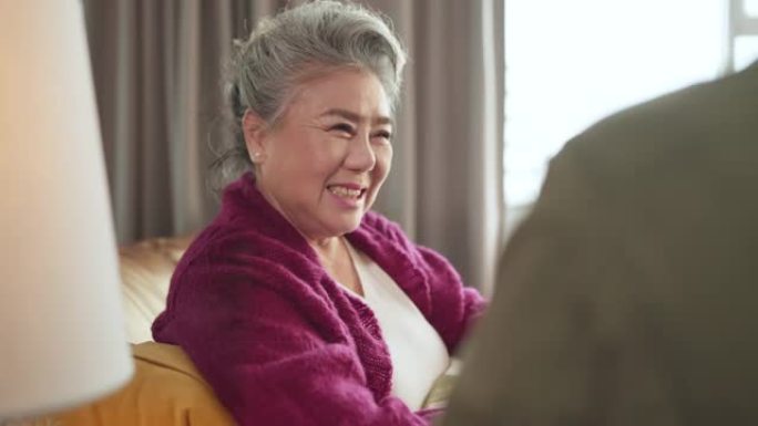 幸福亚洲成人退休女性休闲布放松坐着谈话与家庭假日周末在沙发沙发客厅，亚洲老年女性与家庭关系良好呆在家