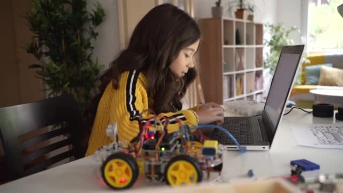 一个白人女学生在她的笔记本电脑上用Arduino平台测试她的机器人汽车原型