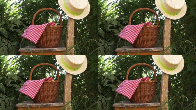 摇摇欲坠的花园椅上带草帽的野餐篮