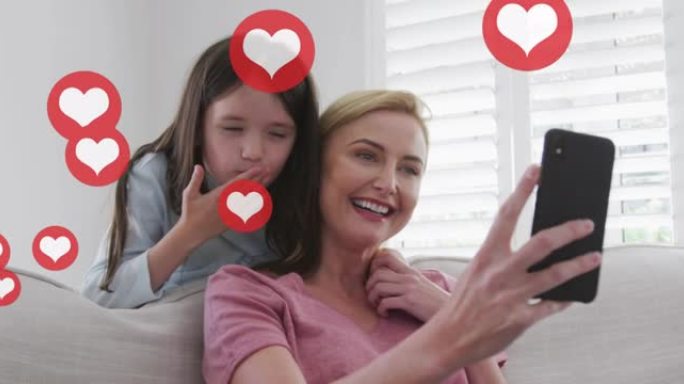 高加索金发母女在家智能手机上聊天的心脏图标动画