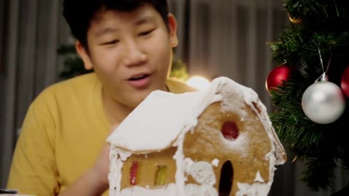 亚洲男孩看完DIY姜饼屋后，圣诞节庆祝生活方式的概念。