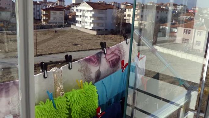 在阳台上晾干衣服的特写镜头，晾衣绳上挂着衣服，阳台上有晾衣夹，