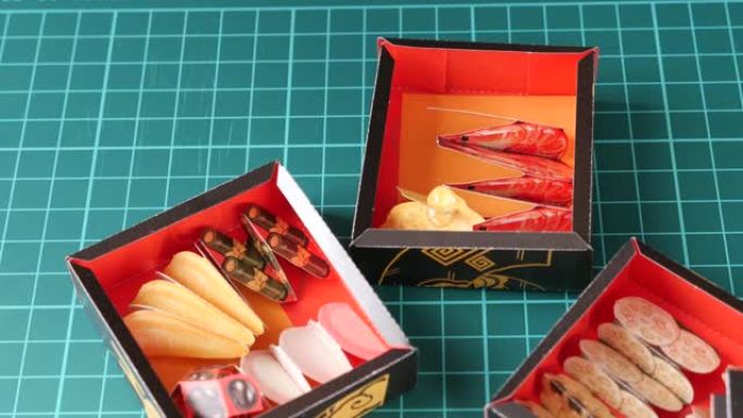 用镊子捏纸制osechi餐具，并将其放在沉重的盒子中。