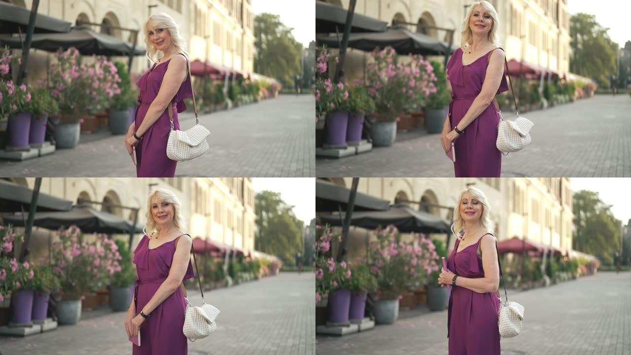 中拍肖像自信的女商人穿着紫色连身衣微笑着看着相机。积极苗条美丽的白人妇女在阳光明媚的早晨在小镇街上的