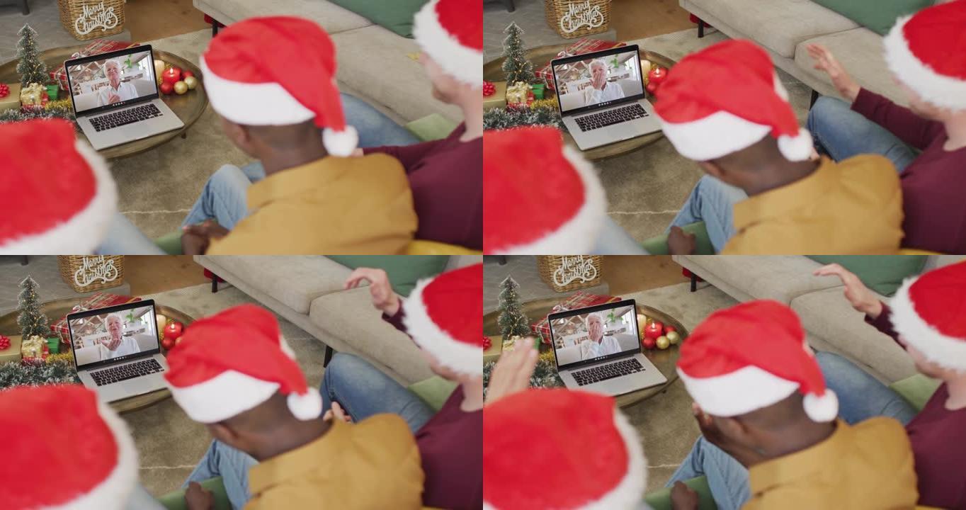 拥有圣诞老人帽子的多元化家庭使用笔记本电脑进行圣诞节视频通话，屏幕上有幸福女人