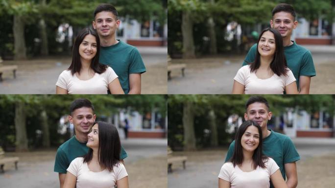 夏天，活泼的年轻夫妇在绿色的街道上站着，拥抱和微笑