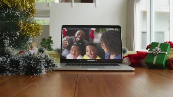 微笑的非裔美国人家庭在笔记本电脑上挥舞着圣诞节视频通话