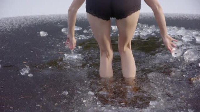 慢动作-年轻女子的美丽腿走进冰冷的水中，跳了出来