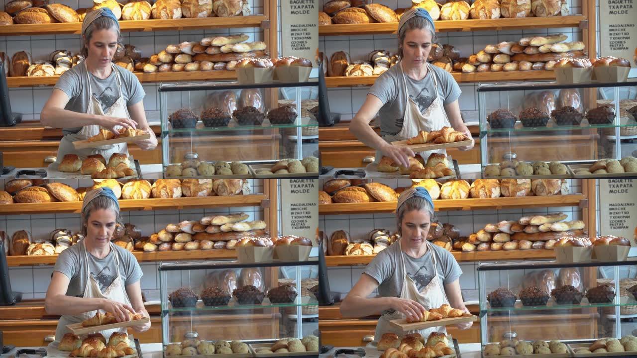 女面包师在面包店的柜台上摆放烘焙食品