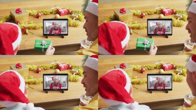 白人父亲和儿子戴着圣诞老人的帽子，使用平板电脑与屏幕上的女人进行圣诞节视频通话