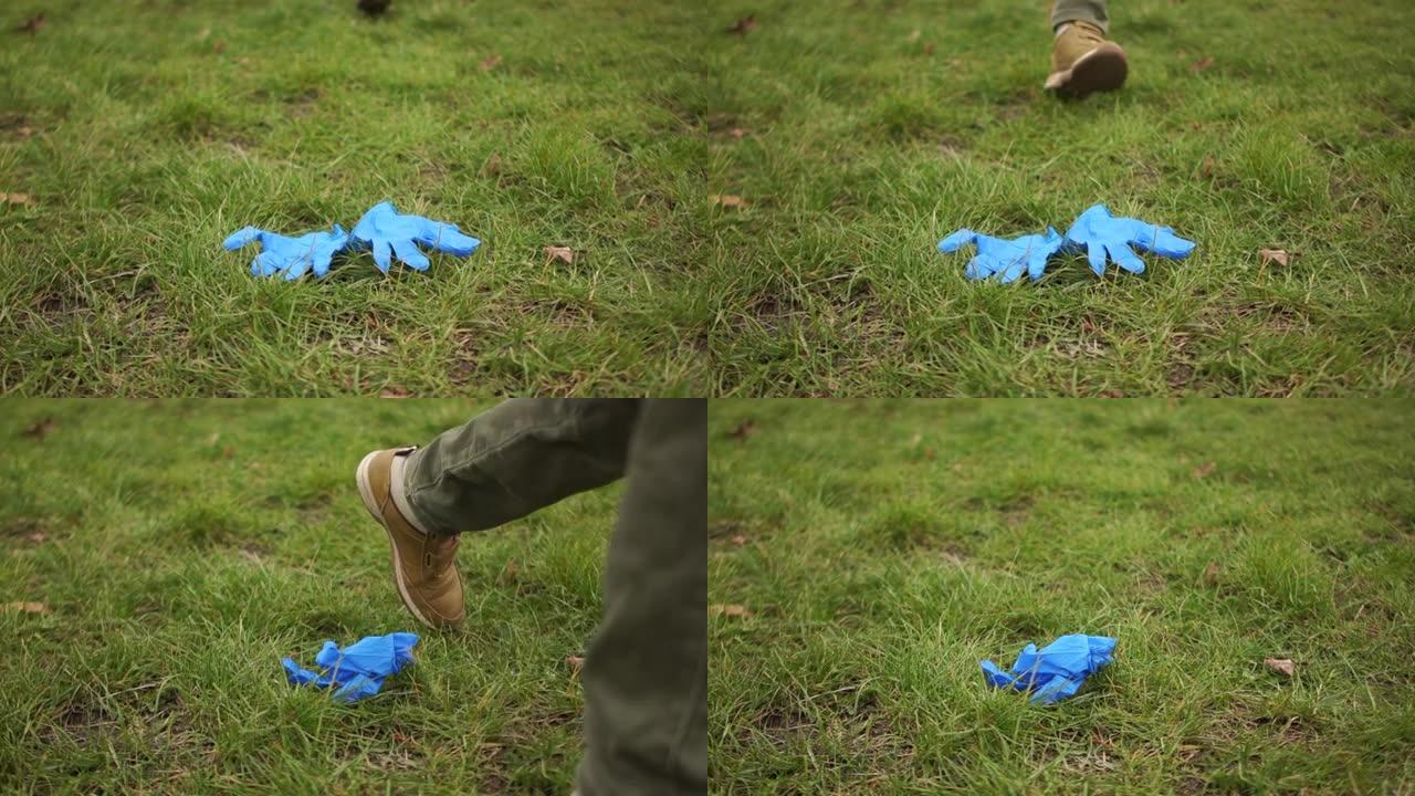 一个无法辨认的少年的腿在草地上踢垃圾，医用防护手套。一次性卫生用品，新型冠状病毒肺炎冠状病毒大流行期