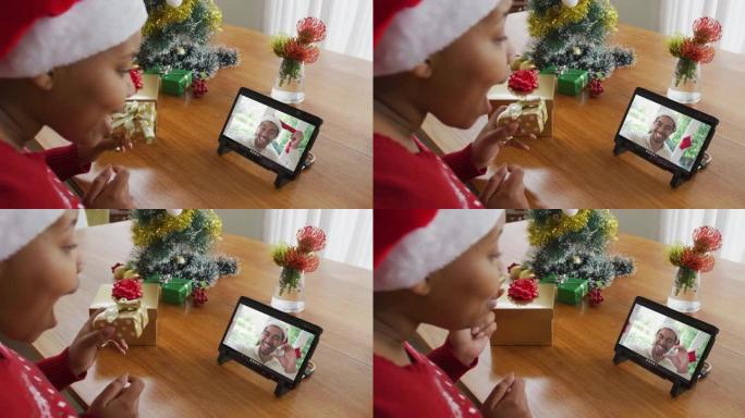 戴着圣诞老人帽子的非洲裔美国妇女使用平板电脑进行圣诞视频通话，屏幕上有男人