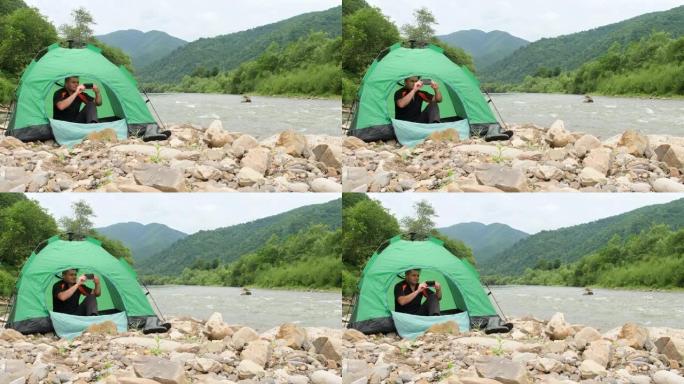 帐篷里的游客在智能手机上捕捉到了山河的美丽景色。