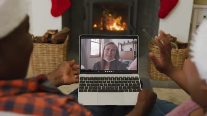 非裔美国人夫妇戴着圣诞老人帽子，使用笔记本电脑与屏幕上的女人进行圣诞节视频通话