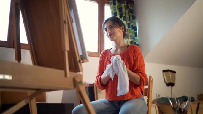 在清洁双手时，自豪的女艺术家欣赏她的艺术作品
