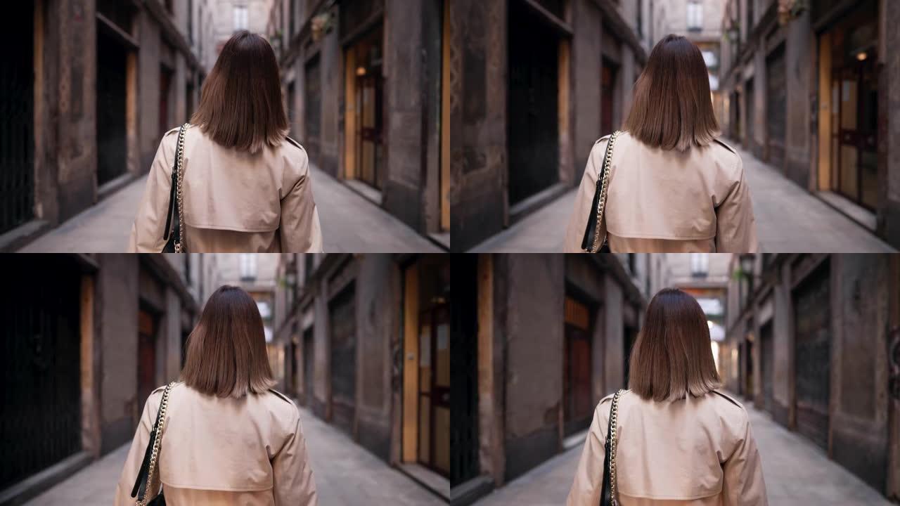 巴塞罗那哥特式区独自行走的女人的背影。旧公寓楼，欧洲狭窄的街道。秋天旅行，穿风衣的女士。