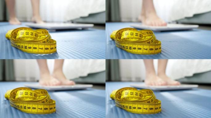 卷尺、健身垫和年轻女子在秤上称重。节食，运动，减肥和健康的生活方式的概念。