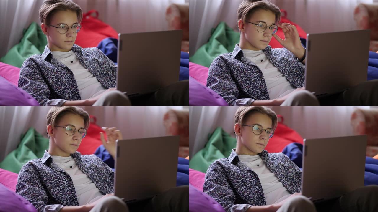一个戴着眼镜的时尚少年看着笔记本电脑屏幕