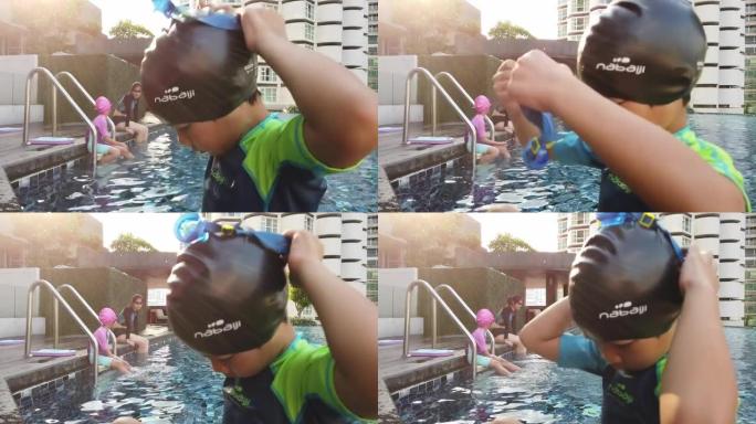 亚洲男孩正在为游泳池游泳戴上泳镜。