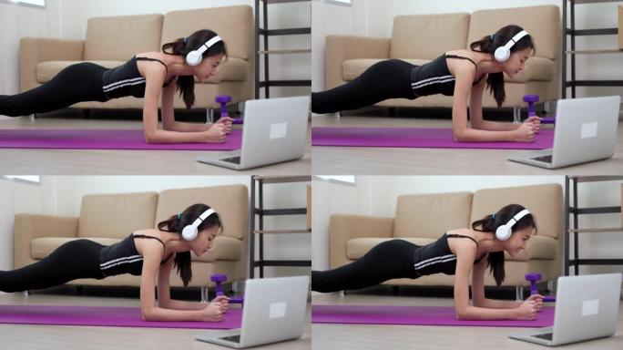 年轻的亚洲妇女在瑜伽垫上做铺板锻炼。体重训练对健康力量和力量。女性健美运动员和家里的肌肉锻炼。生活方