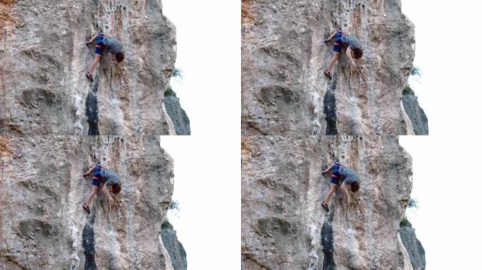 强壮而熟练的男子登山者通过具有挑战性的路线爬上垂直的石灰墙岩壁，登山者处于膝盖位置，双手休息良好，握