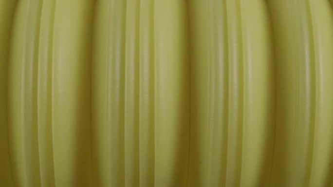 宏观塑料波纹管。压缩弹簧的纹理是特写的。黄色背景。