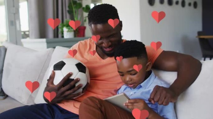 在家里的沙发上使用智能手机在快乐的非洲裔美国父子身上的红心动画