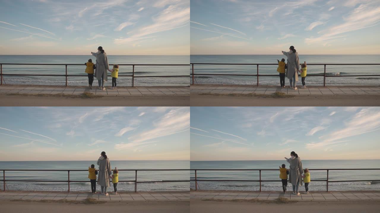 母亲和两个孩子从人行道上看海时的背景图